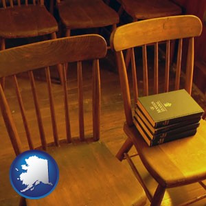 wooden chairs and hymnals in an old church building - with Alaska icon