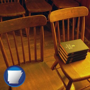 wooden chairs and hymnals in an old church building - with Arkansas icon