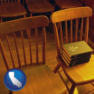 wooden chairs and hymnals in an old church building - with California icon