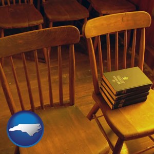 wooden chairs and hymnals in an old church building - with North Carolina icon